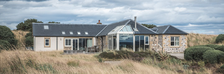 The exterior of the Golf Lodge, between the 14th and 15th fairways of Castle Stuart Golf Links, overlooking the art deco styled clubhouse, the course and the Moray Firth.