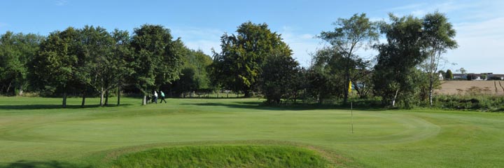 One of the greens at Milnathort Golf Club showing the mature trees that line much of the course
