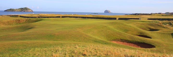 Looking from the tee to the green of the much copied 15th hole on North Berwick West Links. The green slopes from right to left and is guarded by deep pot bunkers. Bass Rock can be seen in the distanc